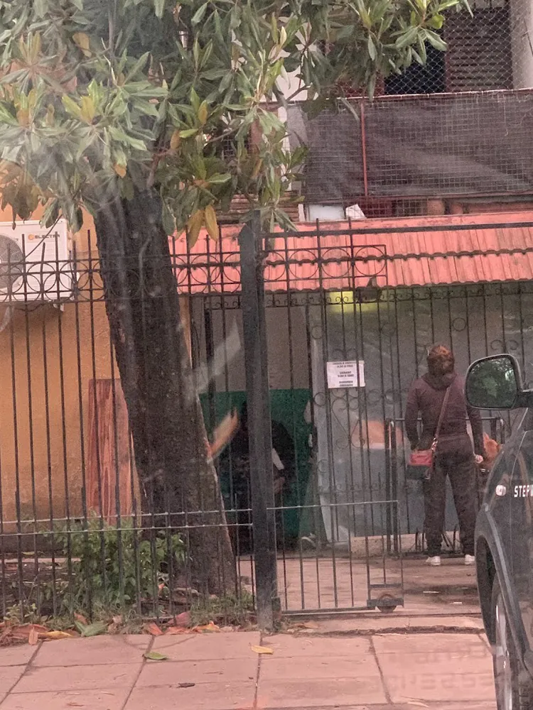 El frente de la veterinaria detrás de una reja negra, bajo un árbol